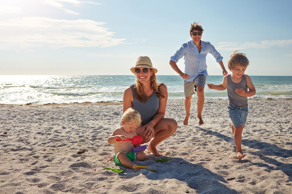 Family playing on the beach while on holiday | Oceania Finance