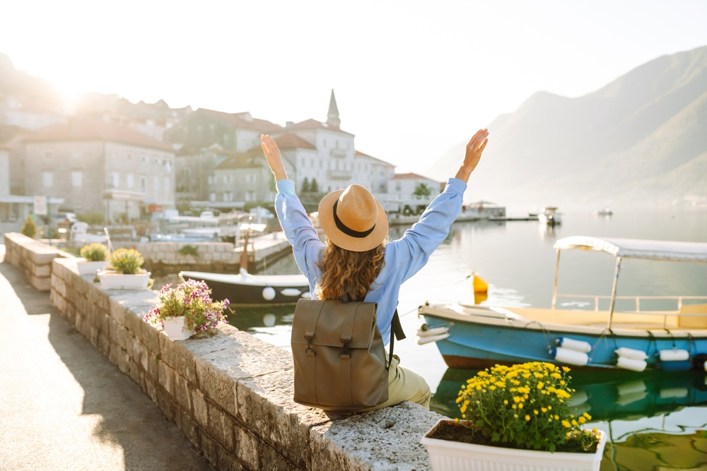 Solo holiday traveller sitting on a bridge enjoying the riverside city view | Oceania Finance